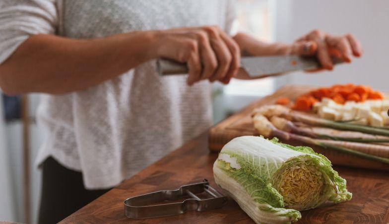 käed hakivad toiduaineid lõikelaual